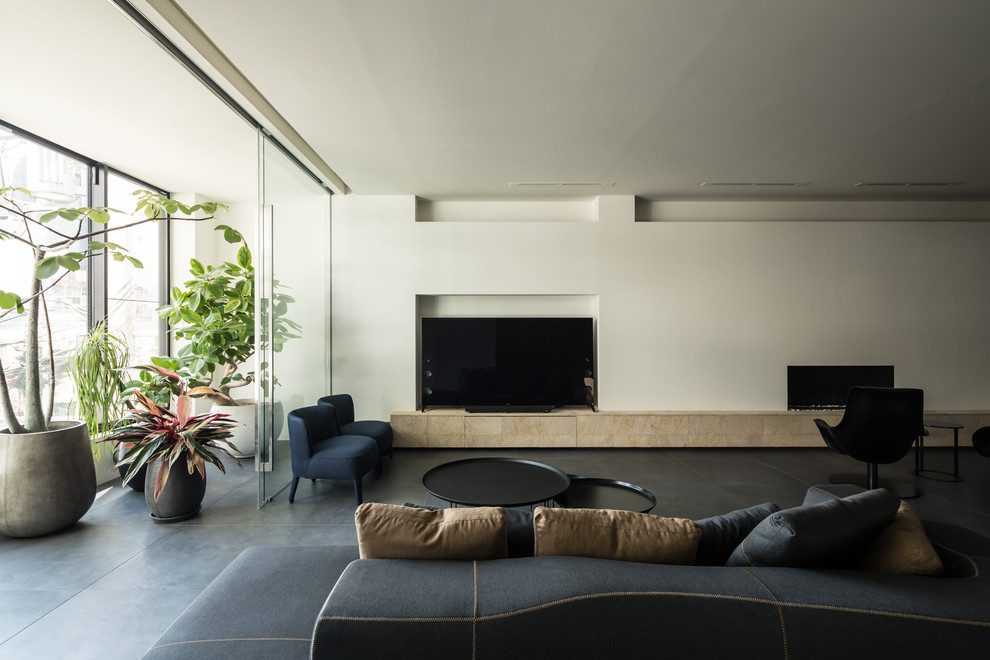На фото: гостиная комната в стиле модернизм с белыми стенами, отдельно стоящим телевизором и черным полом с