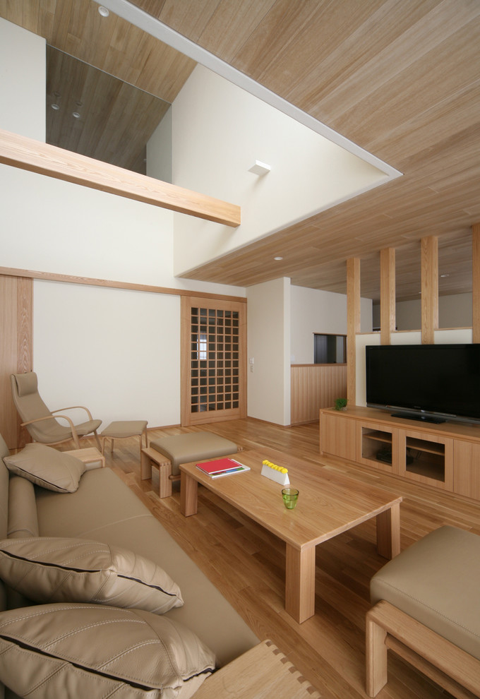 Пример оригинального дизайна: гостиная комната в восточном стиле с белыми стенами, паркетным полом среднего тона, отдельно стоящим телевизором и коричневым полом