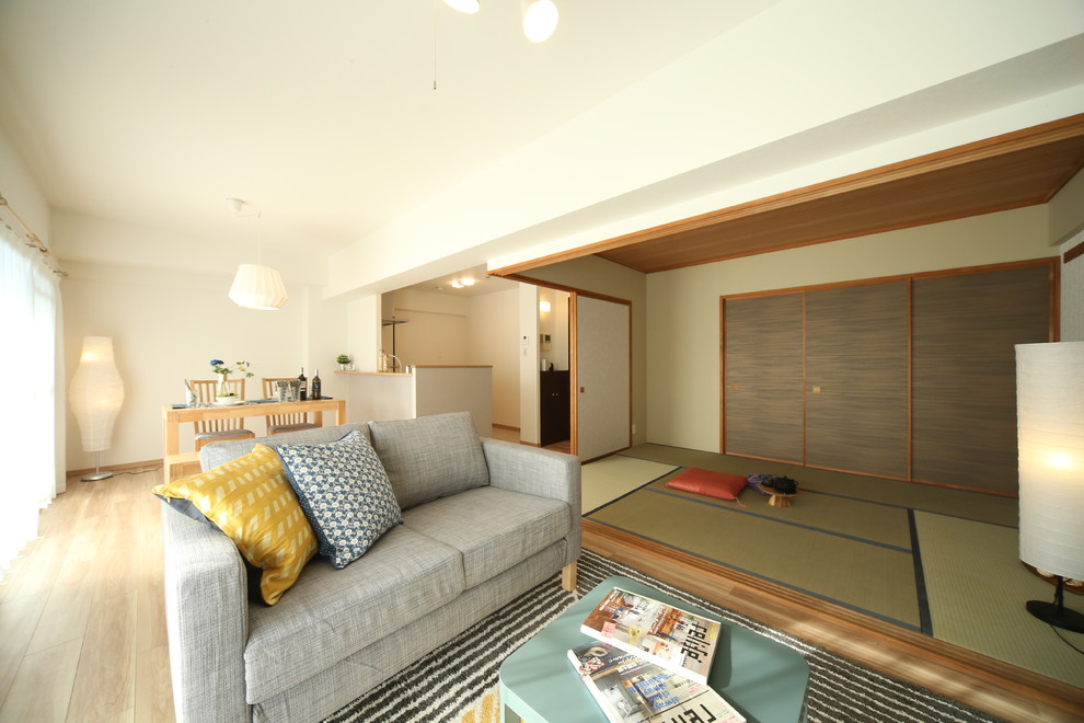 На фото: гостиная комната в восточном стиле с белыми стенами, деревянным полом и бежевым полом с