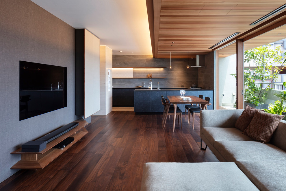 Источник вдохновения для домашнего уюта: открытая гостиная комната в стиле модернизм с разноцветными стенами, темным паркетным полом, телевизором на стене и коричневым полом
