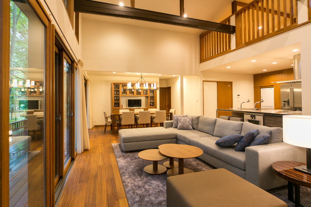 Esempio di un soggiorno country aperto con pareti bianche, pavimento in legno massello medio e pavimento marrone