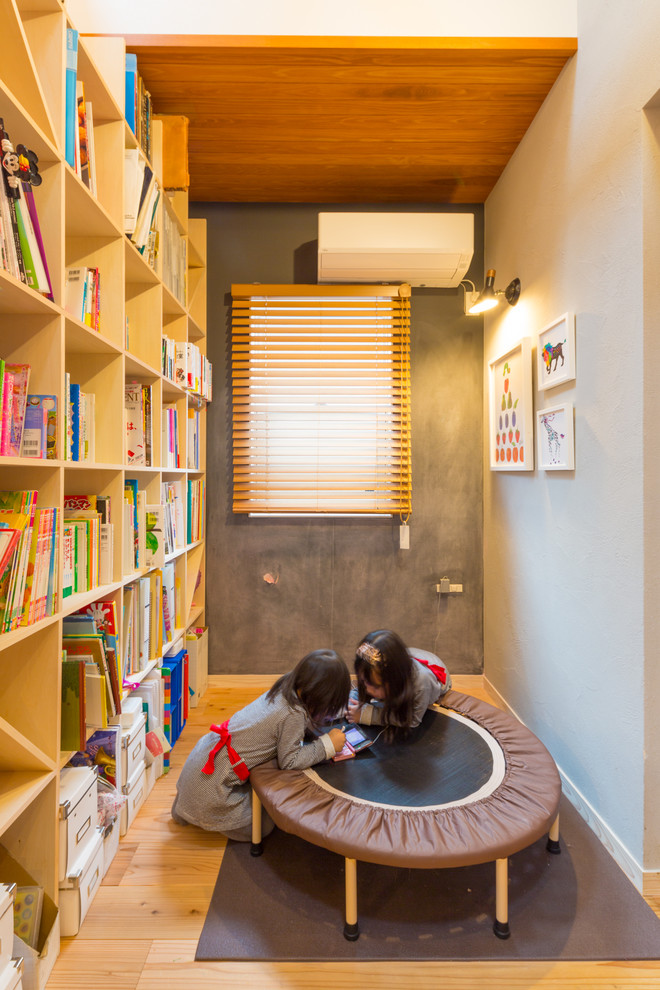 Modelo de biblioteca en casa abierta nórdica de tamaño medio sin chimenea con paredes grises, suelo de madera en tonos medios, televisor independiente y suelo marrón