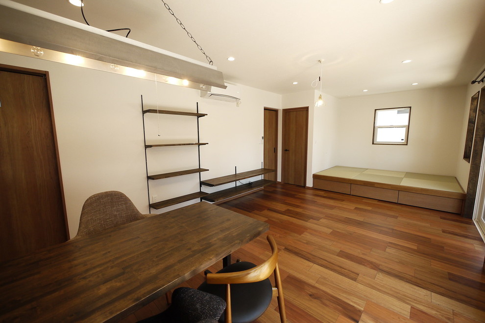 Foto di un soggiorno etnico aperto con pareti bianche, pavimento in compensato, TV autoportante, pavimento marrone e sala formale