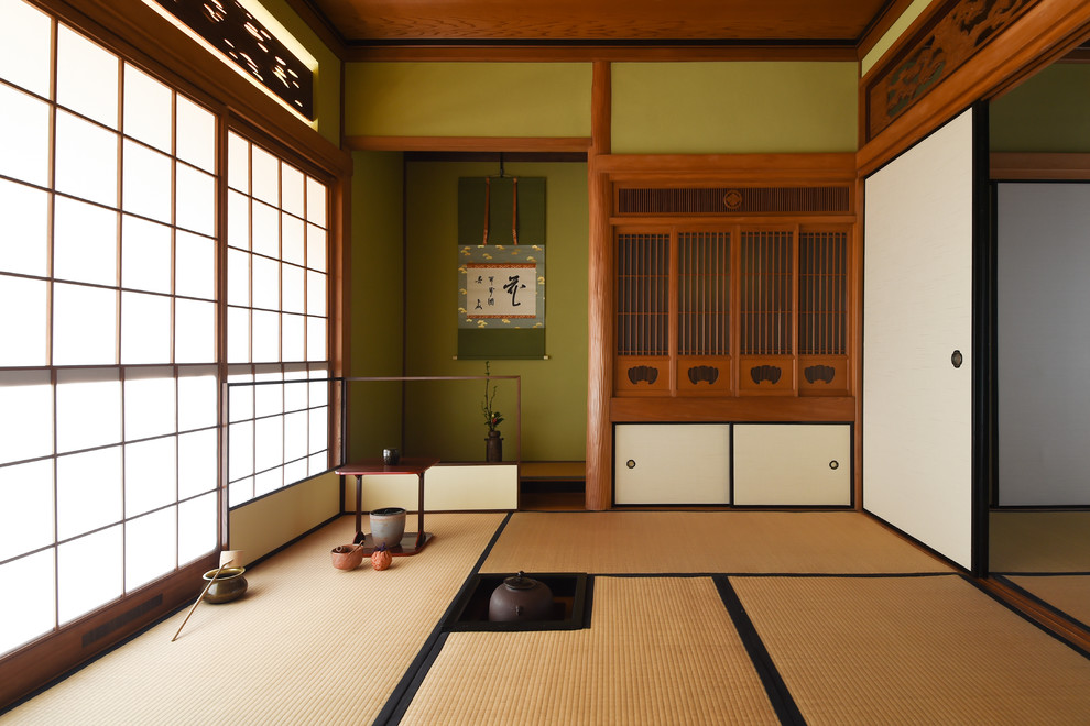 Aménagement d'un salon asiatique avec un mur vert, un sol de tatami et un sol marron.