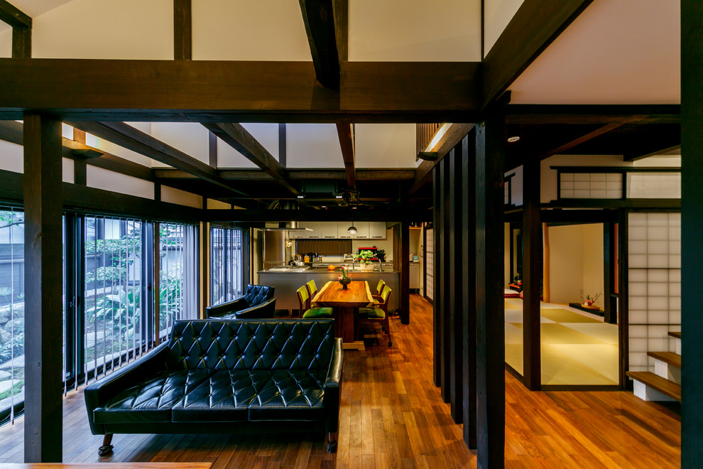 World-inspired open plan living room in Nagoya with white walls, medium hardwood flooring and brown floors.