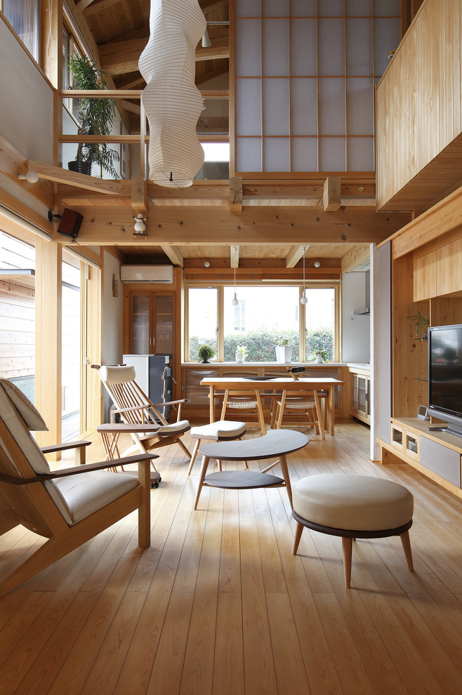 Modelo de salón abierto de estilo zen con paredes blancas, suelo de madera clara y televisor independiente