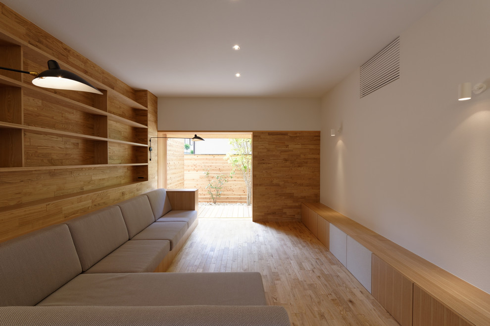 Modern inredning av ett vardagsrum, med ett bibliotek, vita väggar, ljust trägolv och en fristående TV