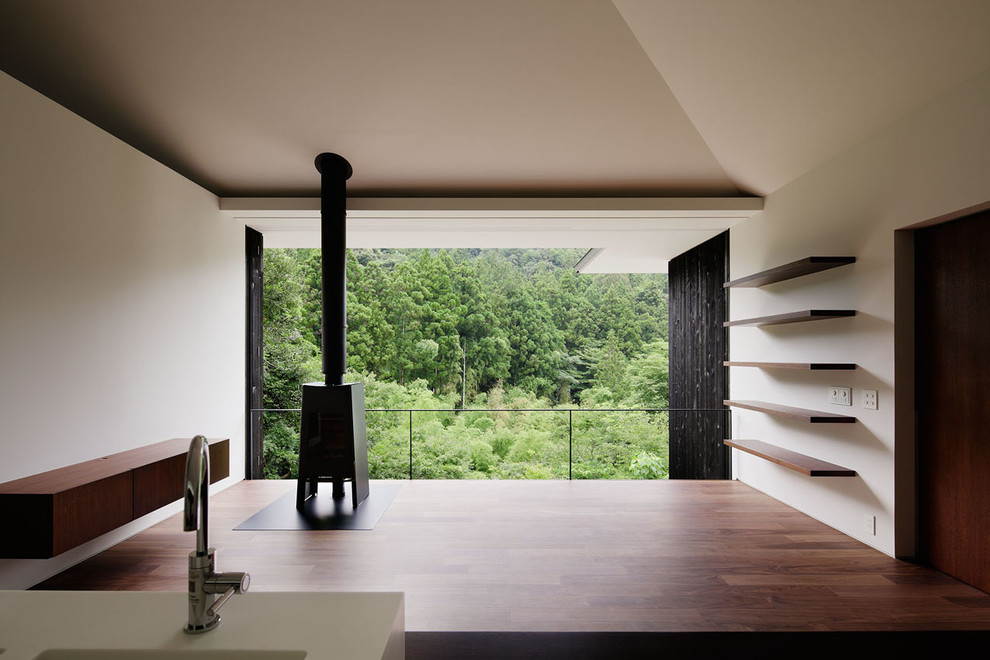 Идея дизайна: открытая гостиная комната в современном стиле с белыми стенами, полом из фанеры, печью-буржуйкой, фасадом камина из металла и коричневым полом
