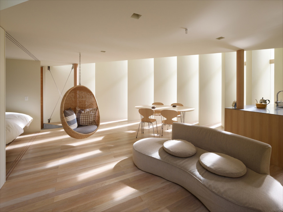 На фото: открытая гостиная комната в современном стиле с белыми стенами, коричневым полом и светлым паркетным полом с