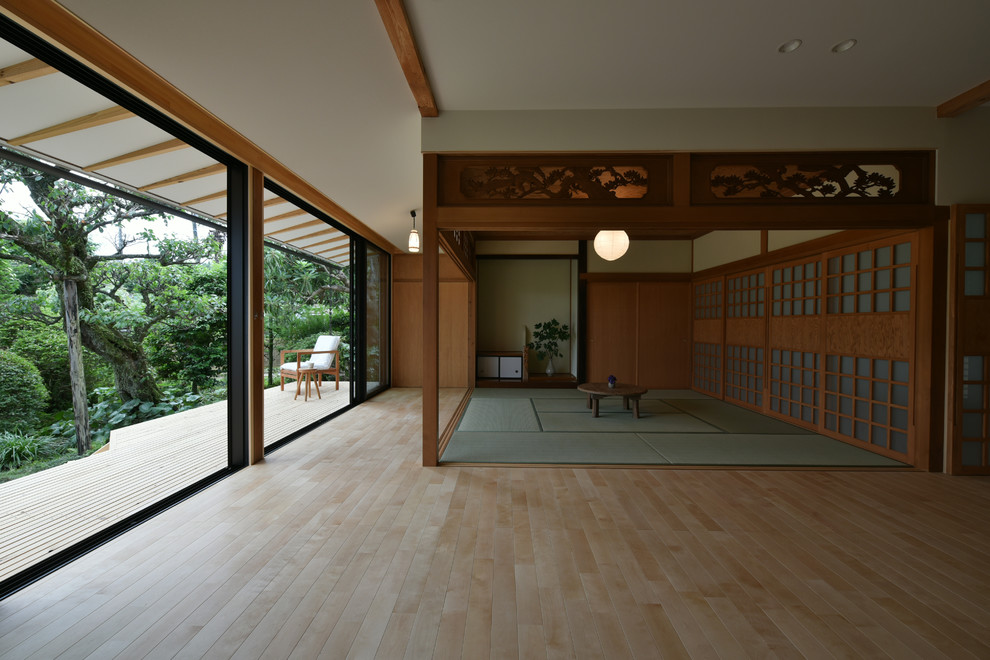 This is an example of a world-inspired open plan living room in Other with white walls, light hardwood flooring, a freestanding tv and brown floors.