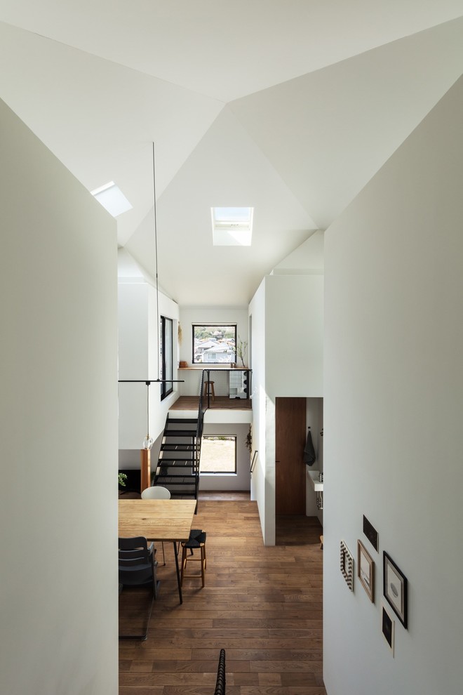 Modern inredning av ett mellanstort allrum med öppen planlösning, med vita väggar, mellanmörkt trägolv och brunt golv