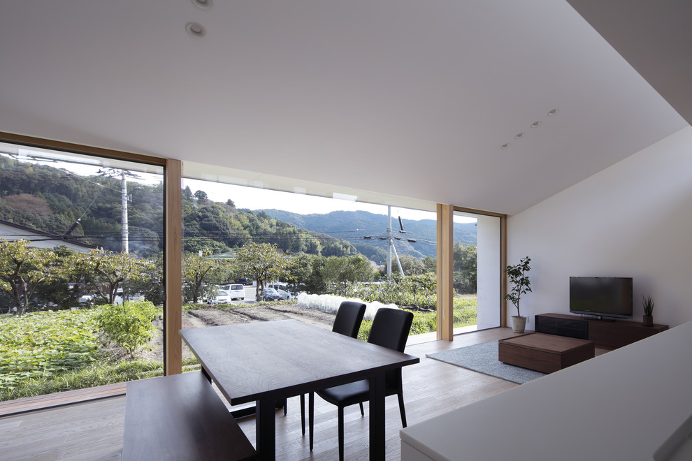 Immagine di un soggiorno moderno aperto con pareti bianche, pavimento in legno massello medio, TV autoportante e pavimento marrone