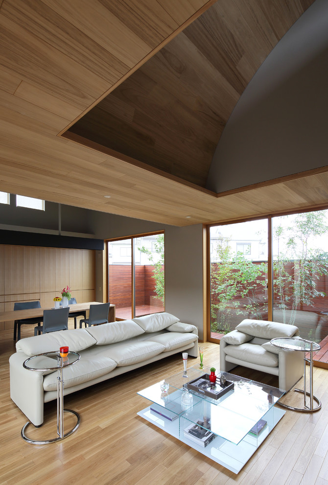 Пример оригинального дизайна: гостиная комната в восточном стиле с серыми стенами, светлым паркетным полом и коричневым полом