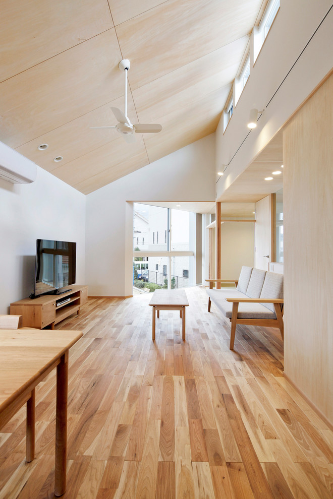 Diseño de salón abierto de estilo zen de tamaño medio con paredes blancas, suelo de madera en tonos medios, televisor independiente y suelo marrón