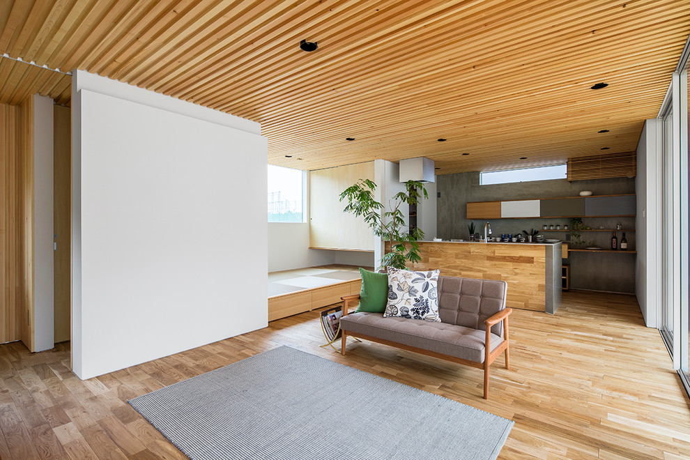 Diseño de salón abierto de estilo zen con paredes blancas, suelo de madera clara y suelo marrón