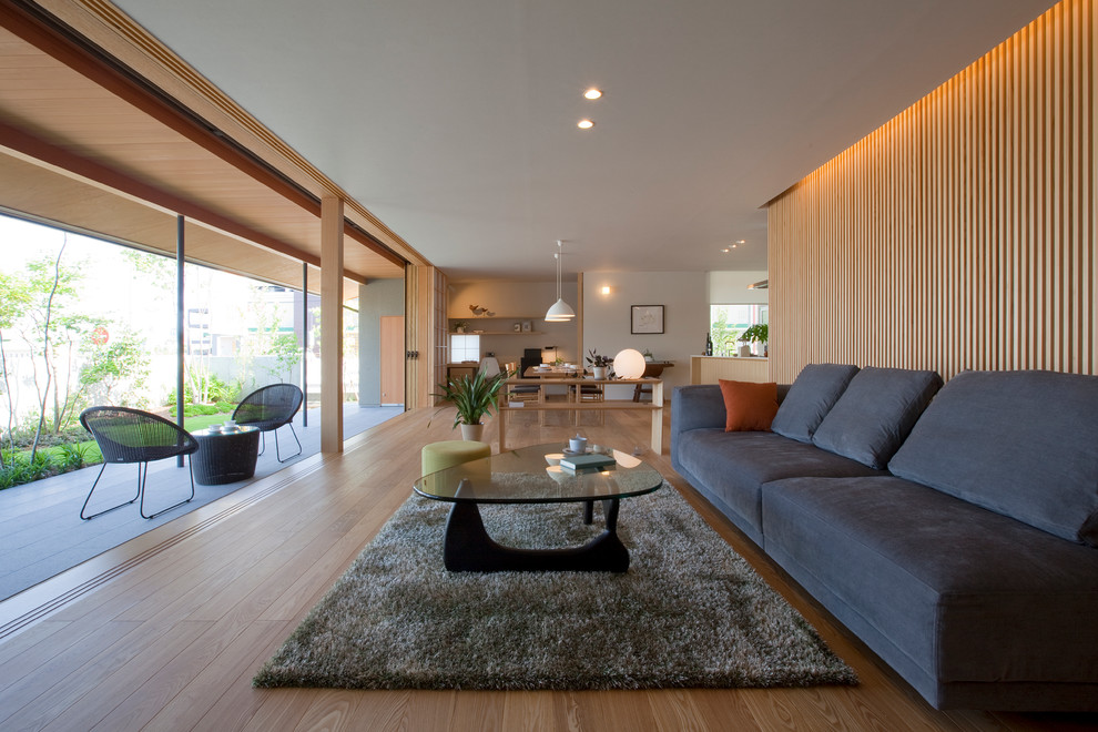 Idée de décoration pour un salon avec un mur blanc et un sol en bois brun.