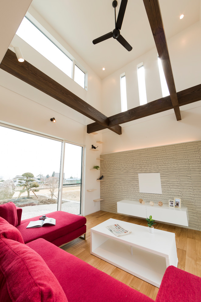 Offenes Modernes Wohnzimmer mit weißer Wandfarbe, braunem Holzboden, TV-Wand und beigem Boden in Sonstige