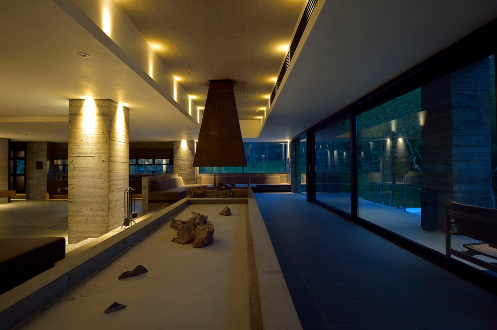 Стильный дизайн: открытая гостиная комната в стиле модернизм с серыми стенами и двусторонним камином - последний тренд
