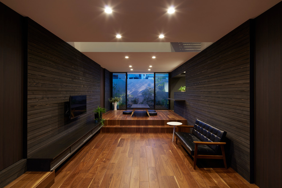 Inspiration för ett funkis vardagsrum, med svarta väggar, mellanmörkt trägolv och en väggmonterad TV