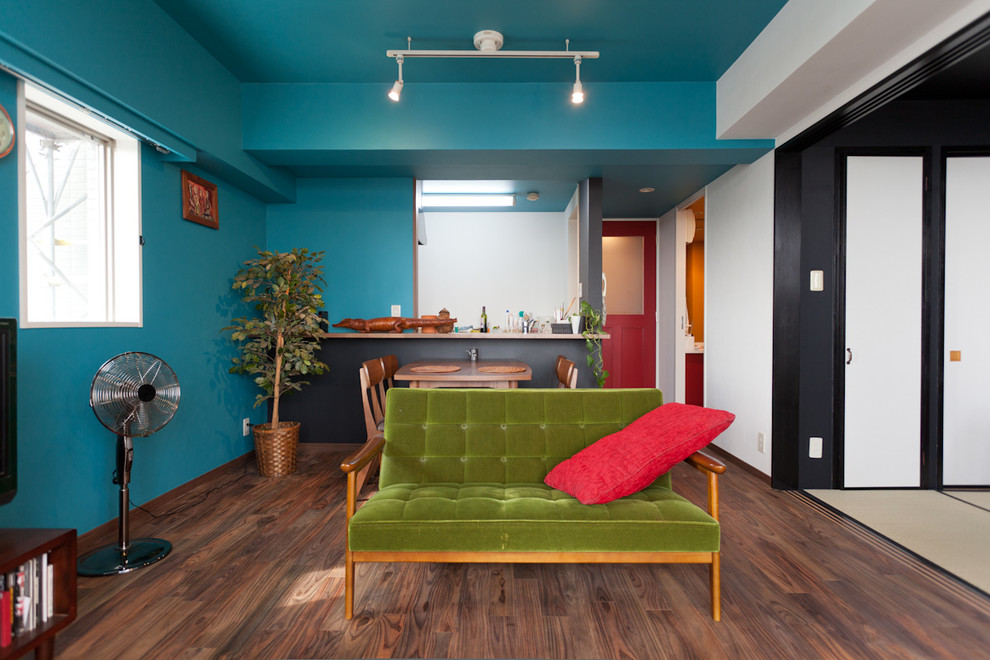 Ejemplo de salón tipo loft asiático pequeño con paredes azules, suelo de madera oscura, televisor independiente y suelo marrón