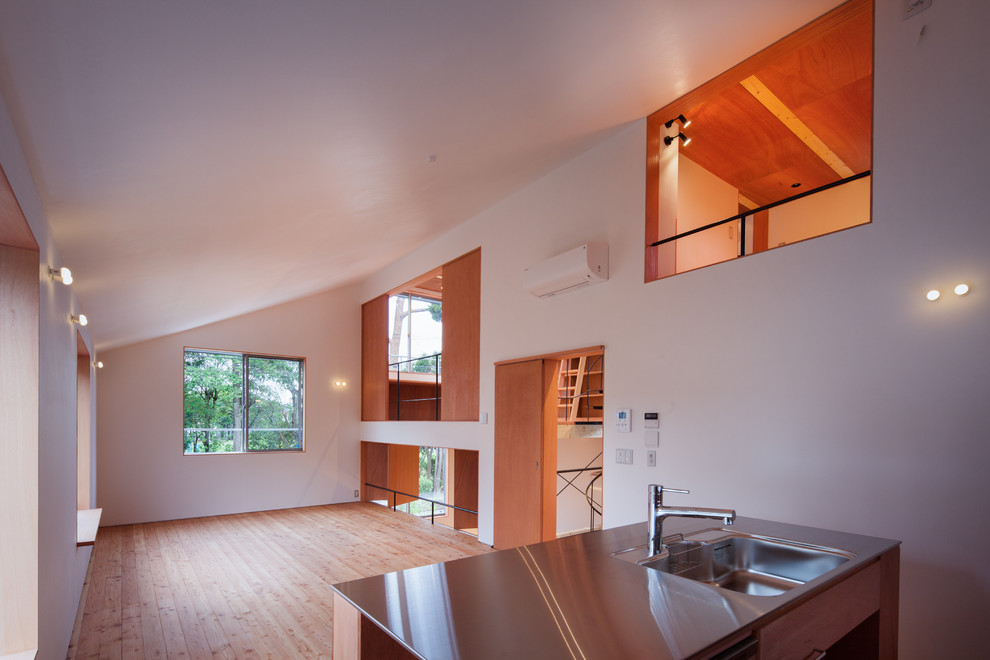 Cette image montre un salon minimaliste de taille moyenne et ouvert avec une salle de réception, un mur blanc, un sol en bois brun, aucune cheminée, un téléviseur indépendant et un sol beige.