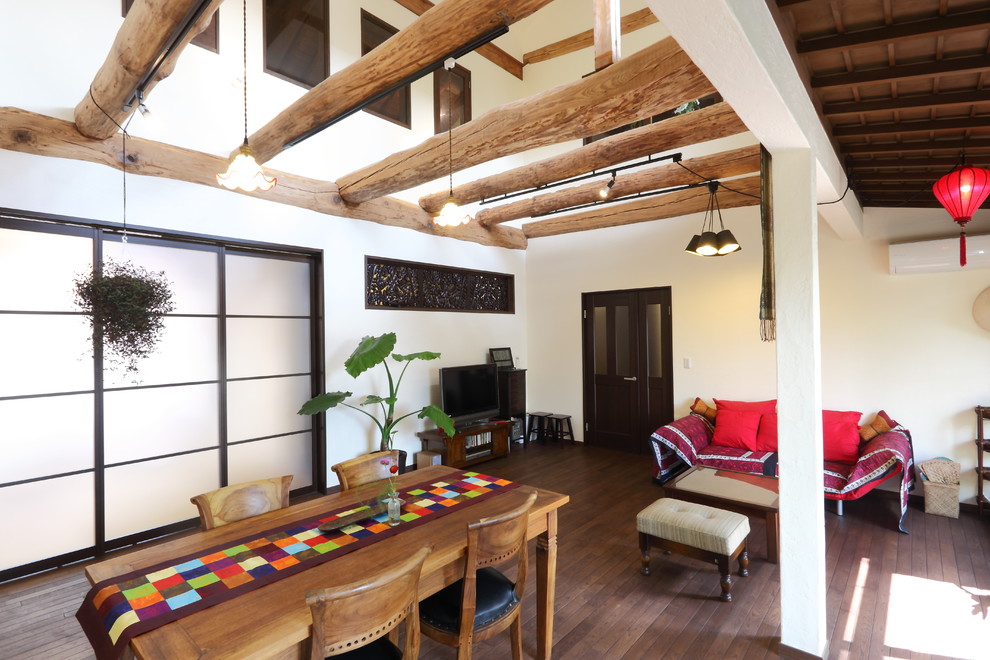 Immagine di un soggiorno etnico con pareti bianche, pavimento in legno massello medio, TV autoportante e pavimento marrone