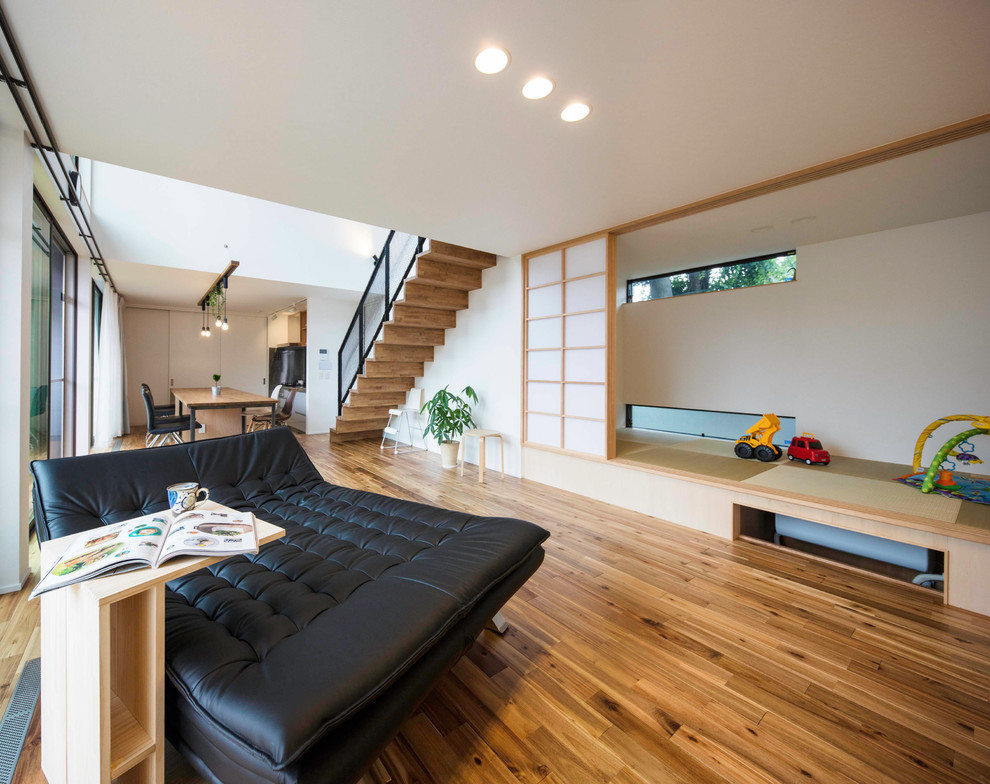 World-inspired open plan living room in Tokyo with white walls, medium hardwood flooring and brown floors.