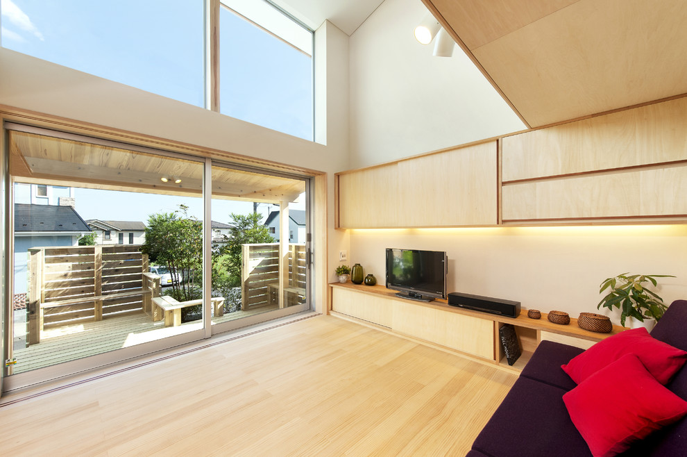 Modernes Wohnzimmer mit beiger Wandfarbe, hellem Holzboden, freistehendem TV und beigem Boden in Sonstige