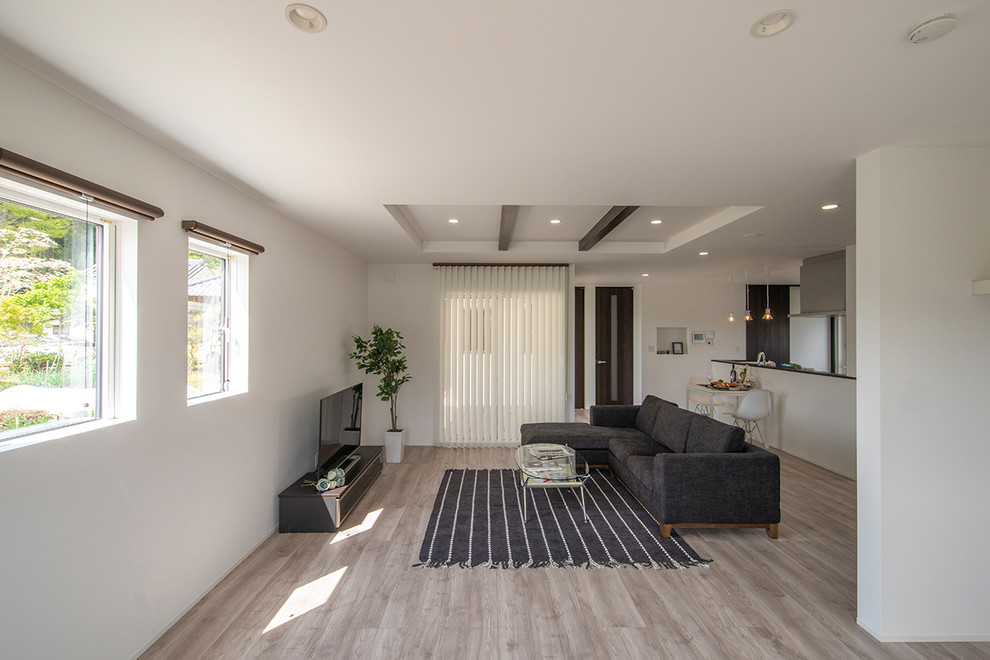 На фото: гостиная комната в стиле модернизм с белыми стенами, полом из фанеры и отдельно стоящим телевизором без камина