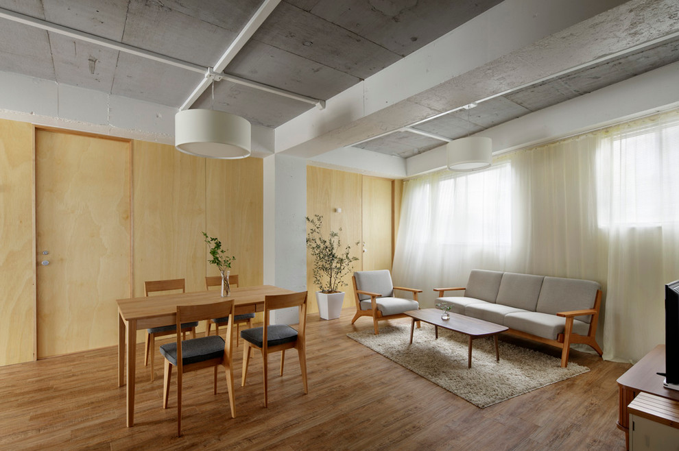 Cette image montre un salon asiatique ouvert avec un mur blanc, un sol en bois brun et un téléviseur indépendant.
