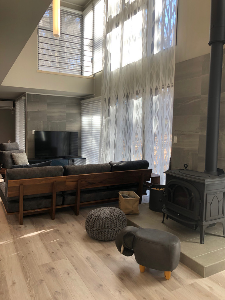 Imagen de salón para visitas moderno grande con paredes grises, suelo de contrachapado, suelo gris y televisor independiente