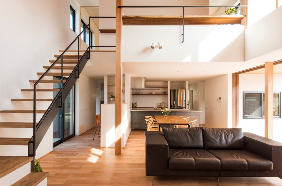 Cette image montre un salon design ouvert avec un mur blanc, un sol en bois brun et un sol marron.