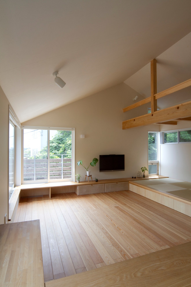 Offenes Skandinavisches Wohnzimmer mit weißer Wandfarbe, braunem Holzboden, TV-Wand und beigem Boden in Sonstige