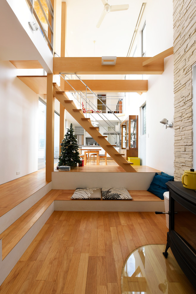 Diseño de salón abierto actual sin televisor con paredes blancas, suelo de madera en tonos medios y estufa de leña
