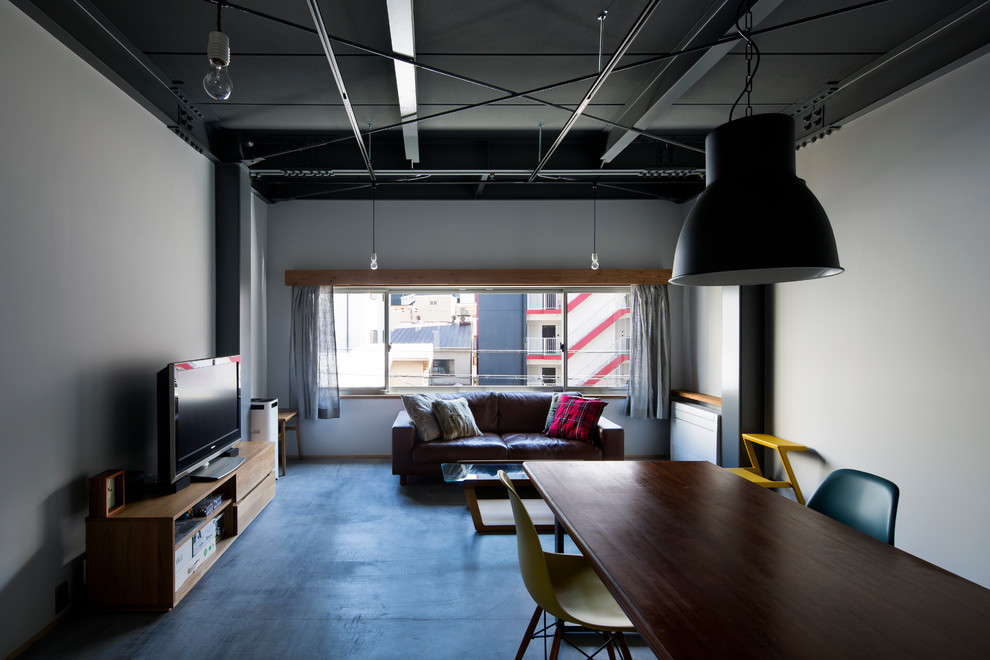 Exempel på ett litet industriellt allrum med öppen planlösning, med grå väggar, betonggolv, grått golv och en fristående TV