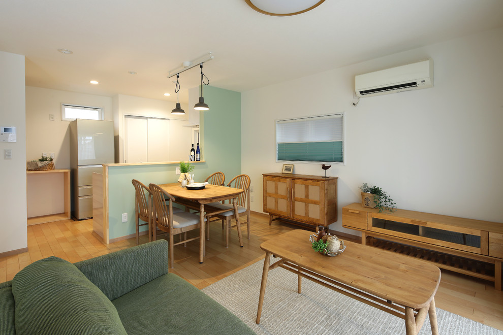 Kleines Asiatisches Wohnzimmer mit weißer Wandfarbe, freistehendem TV, beigem Boden und braunem Holzboden in Sonstige
