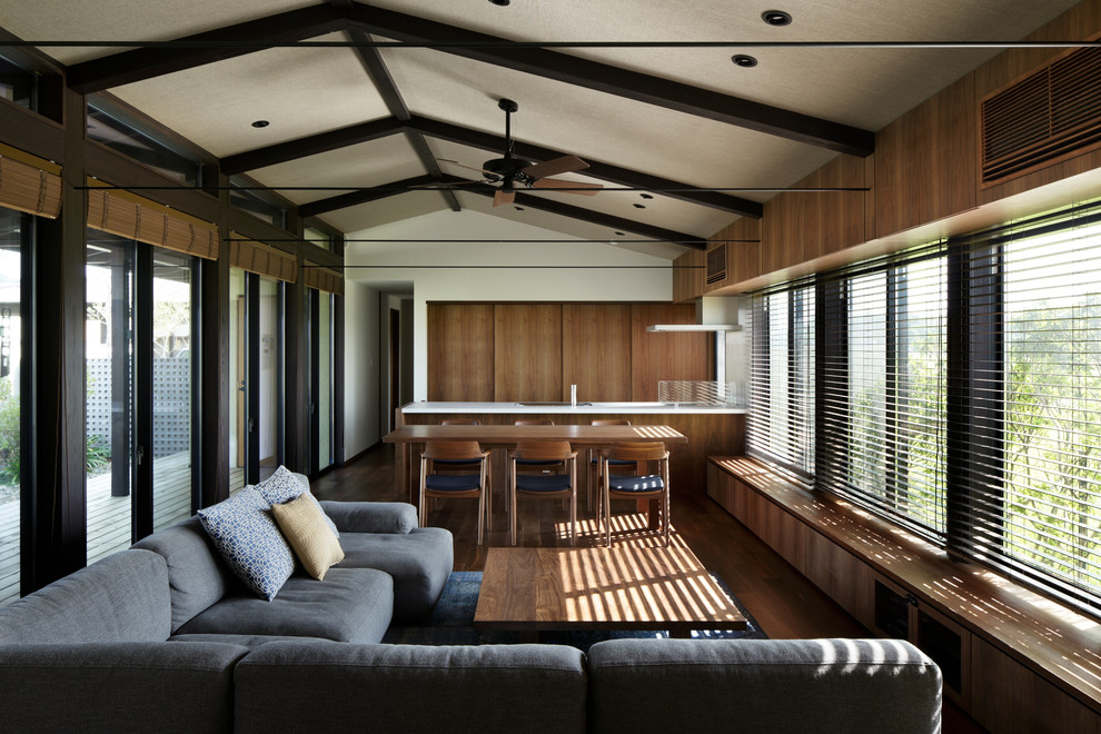 Cette image montre un salon minimaliste ouvert avec un mur marron, un sol en bois brun, aucune cheminée et aucun téléviseur.