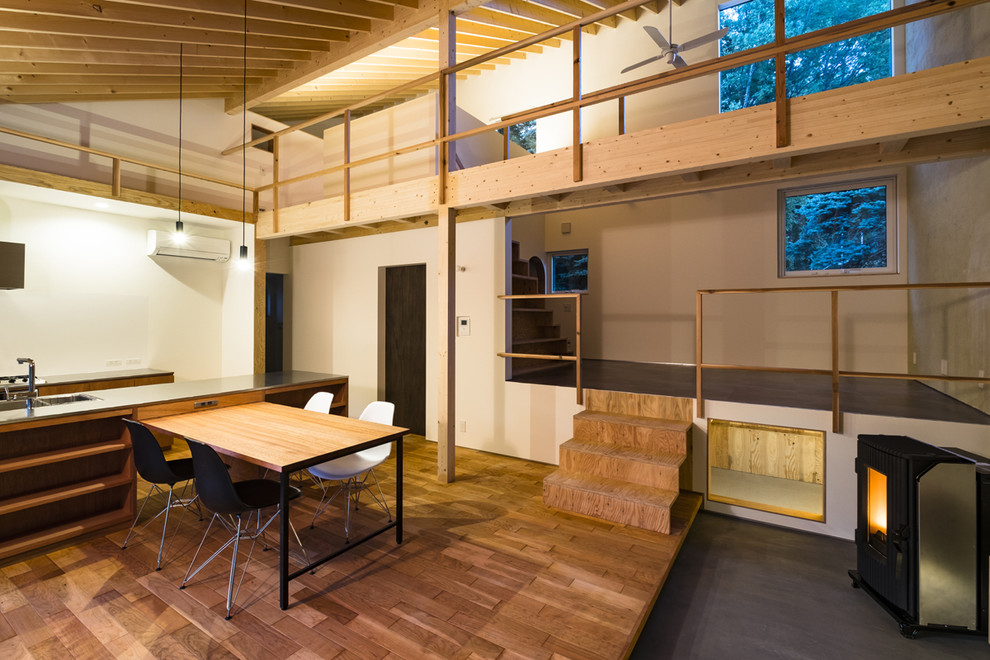 Idée de décoration pour un salon design ouvert avec un mur blanc, un sol en bois brun, un poêle à bois et un sol marron.
