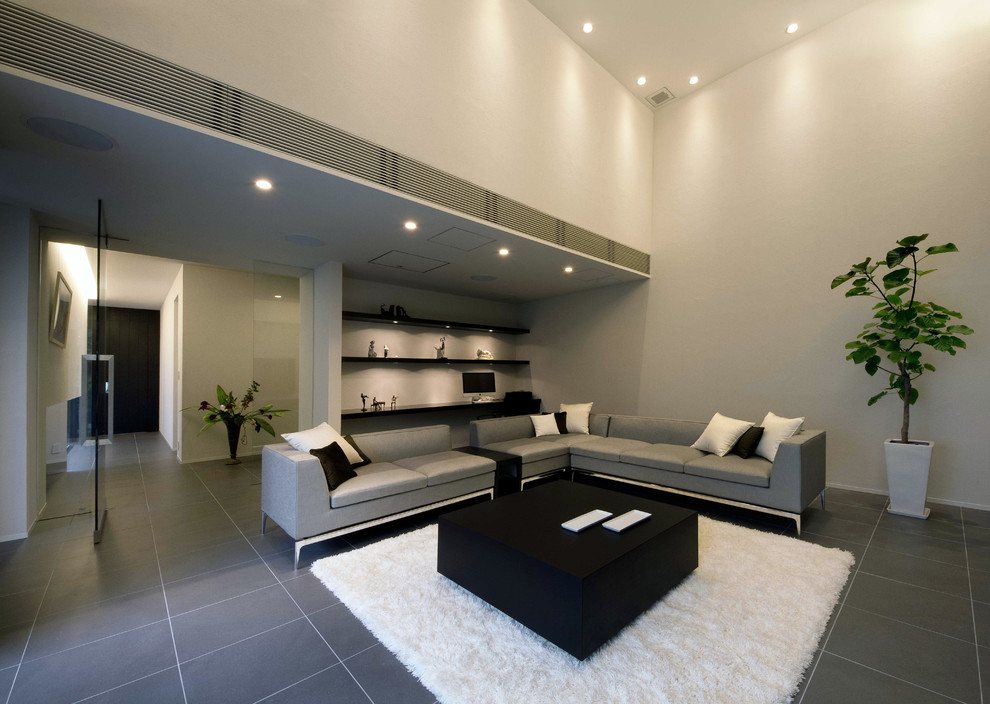 Ejemplo de salón para visitas cerrado minimalista grande sin chimenea con paredes grises, suelo de pizarra y televisor independiente