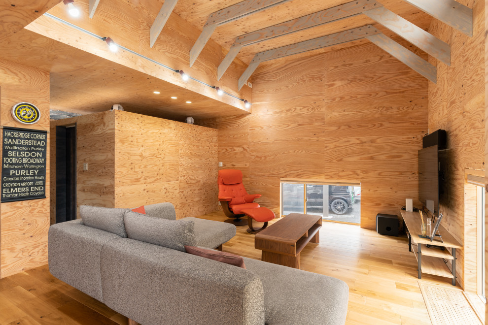 Foto di un soggiorno etnico aperto con pareti marroni, pavimento in legno massello medio, TV a parete e pavimento marrone