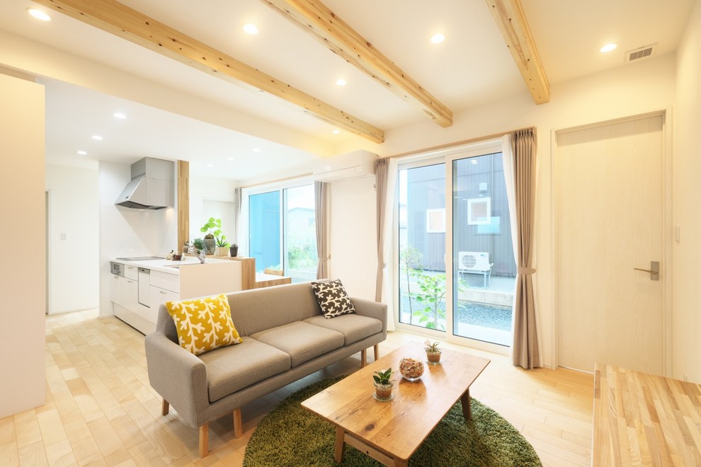 Foto de salón abierto moderno de tamaño medio sin chimenea con paredes blancas, suelo de madera clara, televisor colgado en la pared y suelo beige