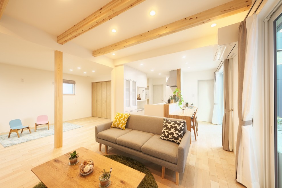 Imagen de salón abierto minimalista de tamaño medio sin chimenea con paredes blancas, suelo de madera clara, televisor colgado en la pared y suelo beige