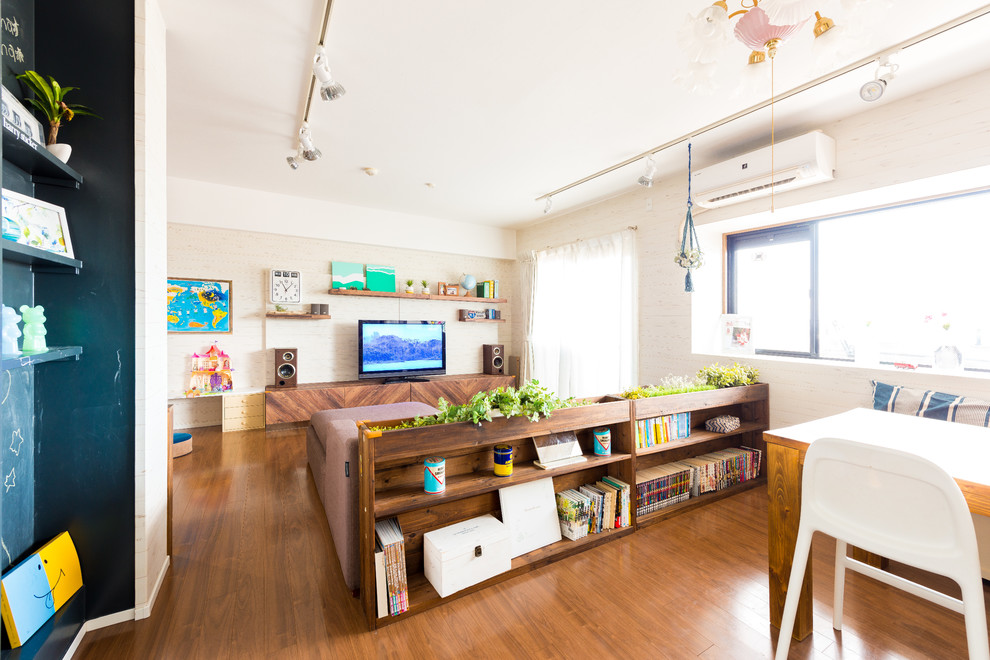 На фото: открытая гостиная комната в стиле фьюжн с белыми стенами, полом из фанеры, отдельно стоящим телевизором и коричневым полом без камина с