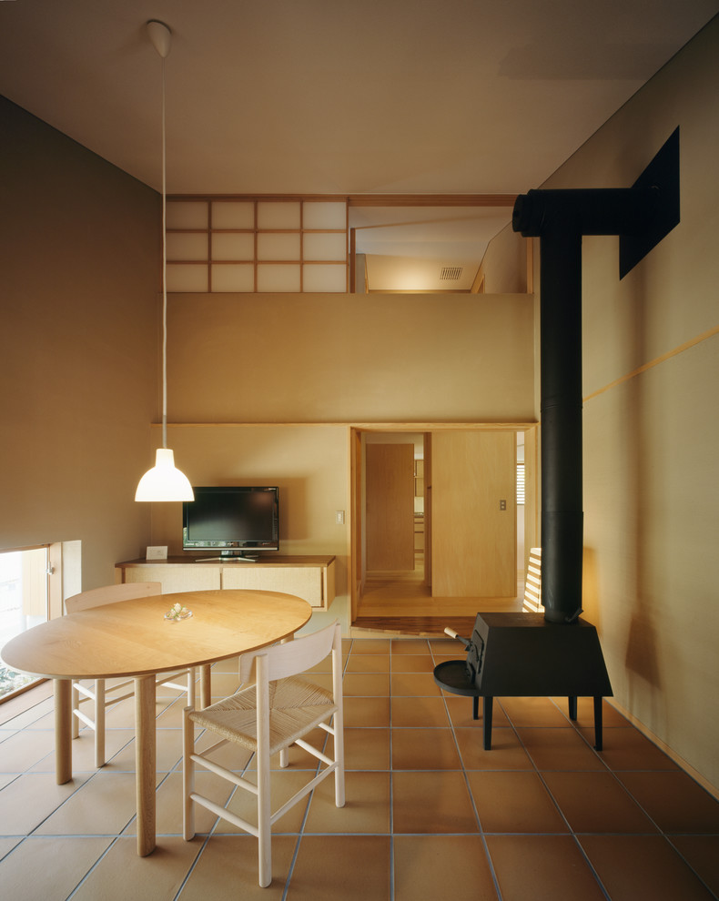 Aménagement d'un salon asiatique avec un mur beige, un poêle à bois et un téléviseur indépendant.