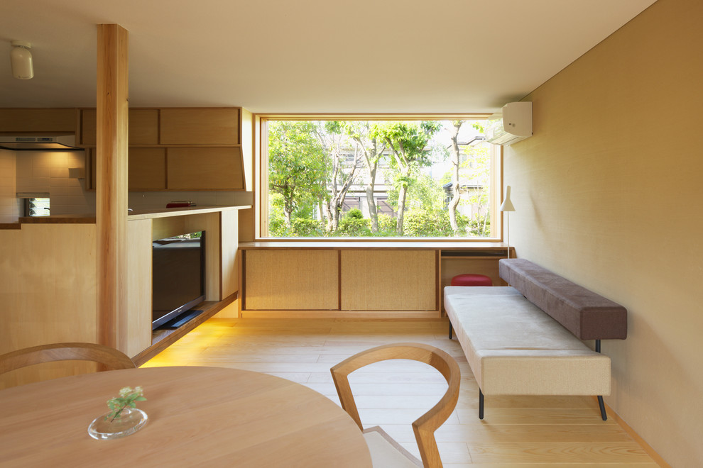 Modelo de salón abierto de estilo zen con paredes beige, suelo de madera clara y televisor independiente