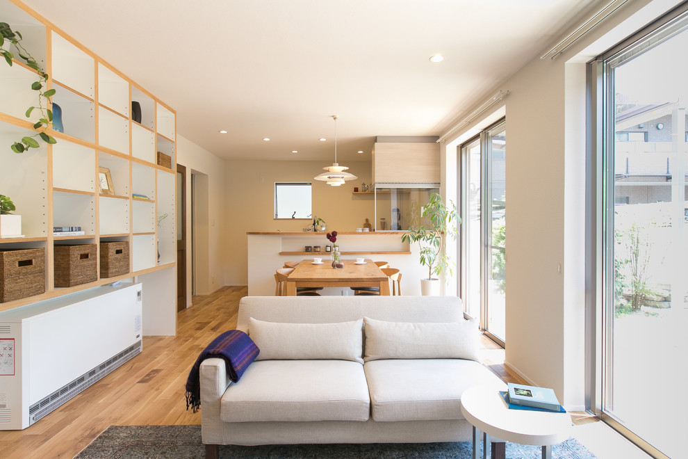Modelo de salón abierto contemporáneo con paredes beige, suelo de madera en tonos medios y suelo marrón