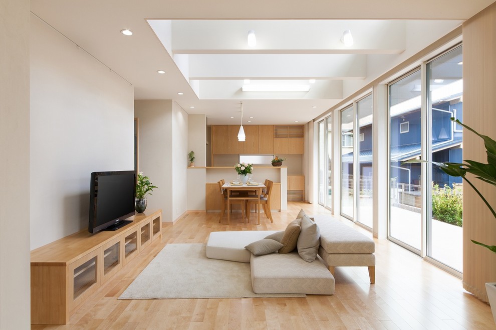 Bild på ett nordiskt vardagsrum, med vita väggar, ljust trägolv, en fristående TV och brunt golv