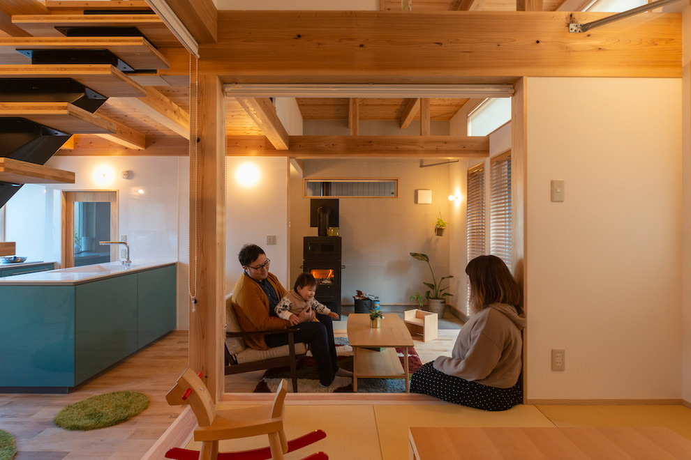 Cette photo montre un salon ouvert avec un mur blanc, un sol de tatami et un poêle à bois.
