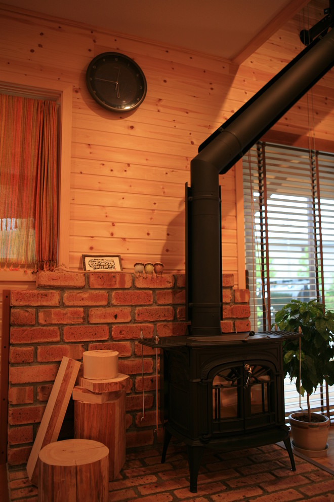 Immagine di un soggiorno country con stufa a legna e cornice del camino in mattoni