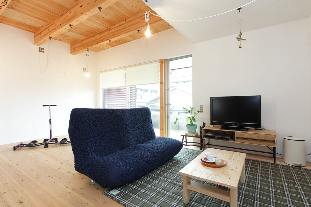 На фото: гостиная комната в восточном стиле с белыми стенами, светлым паркетным полом, отдельно стоящим телевизором и коричневым полом